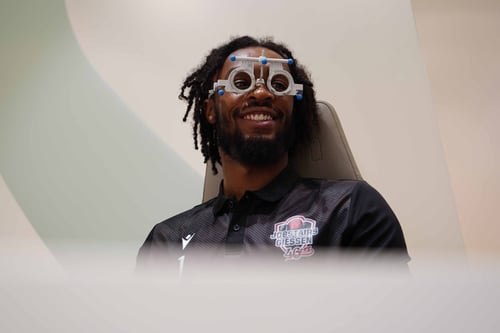 Mann trägt eine Messbrille während eines Sehtests und lächelt