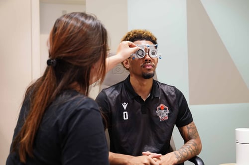 Optikerin passt die Messbrille eines Mannes während eines Sehtests an