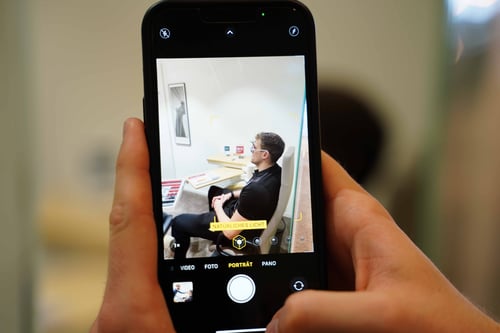 Blick auf einen Mann durch die Kameraansicht eines Smartphones
