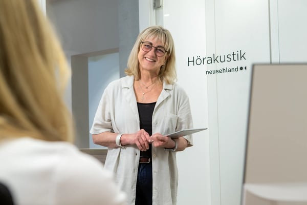 Frau mit Tablet steht im Empfangsbereich der Hörakustik