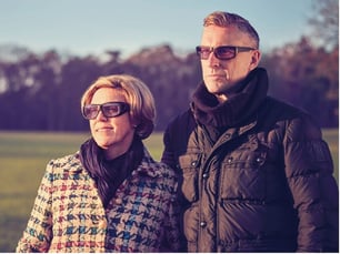 Mann und Frau tragen Sonnenbrillen bei einem Spaziergang im Freien.