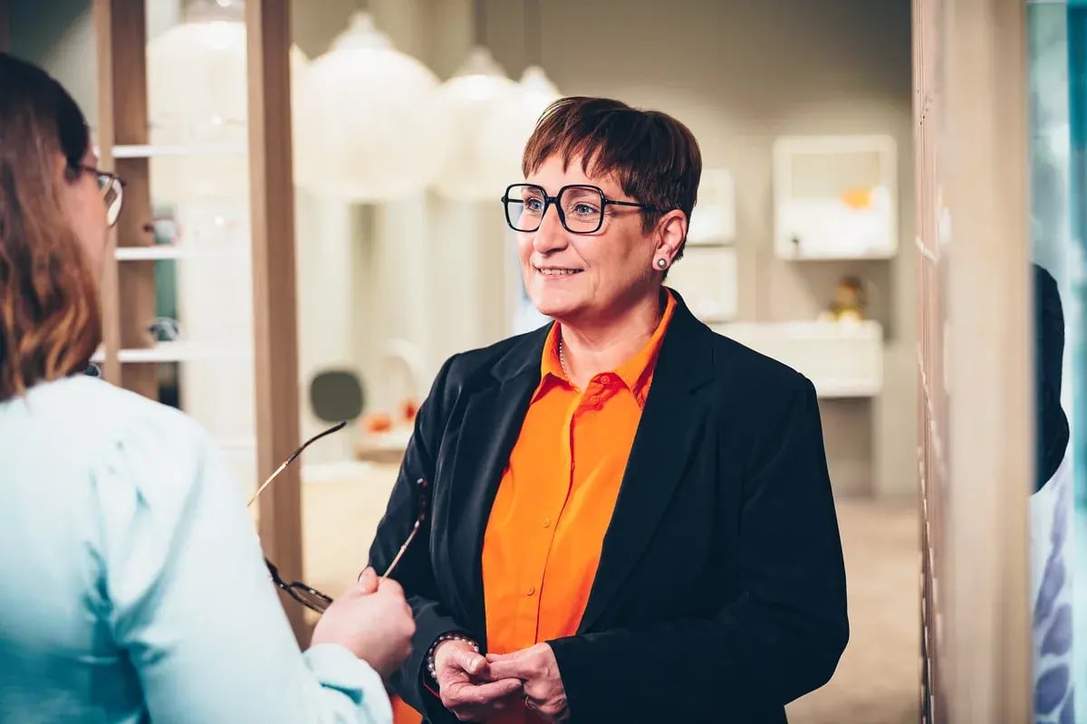 Optikerin berät eine Kundin bei der Brillenauswahl in einem Geschäft
