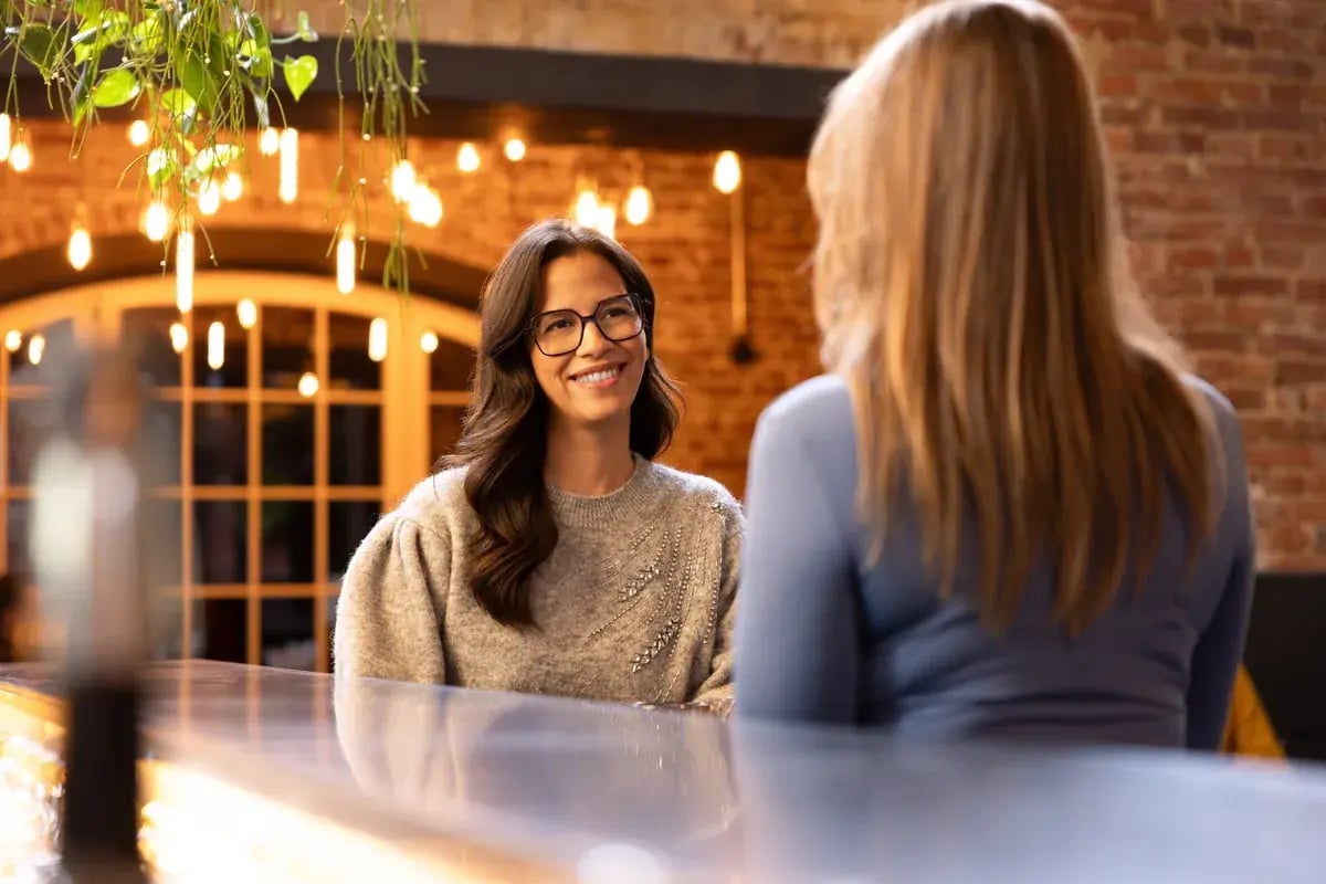 Frau mit Damenbrille sitzt in einem warm beleuchteten Restaurant