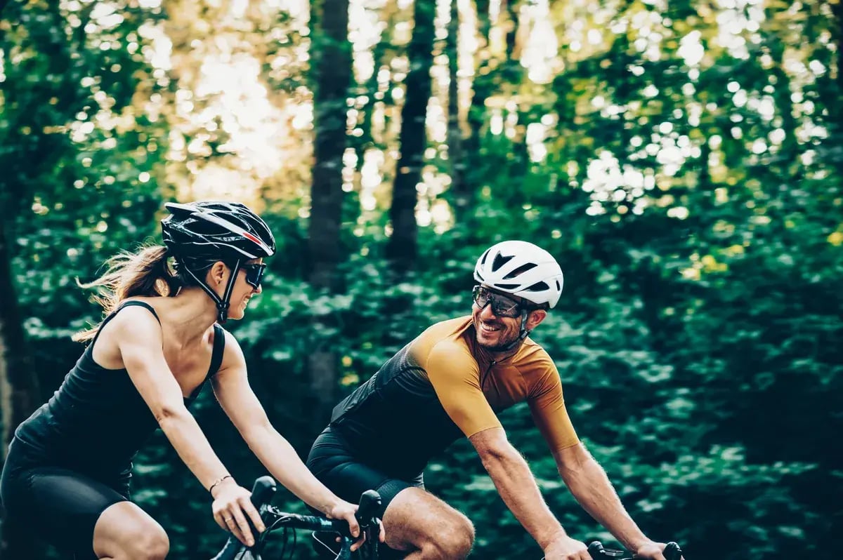 Paar mit Sportbrillen fährt Fahrrad auf einem Waldweg