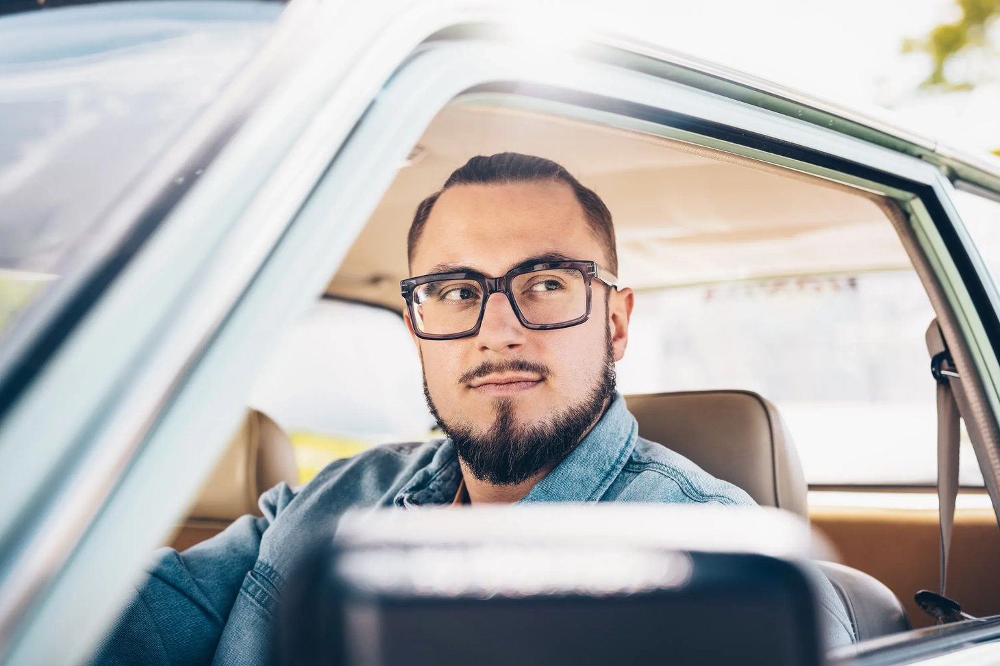 Mann mit Herrenbrille sitzt entspannt in einem Auto