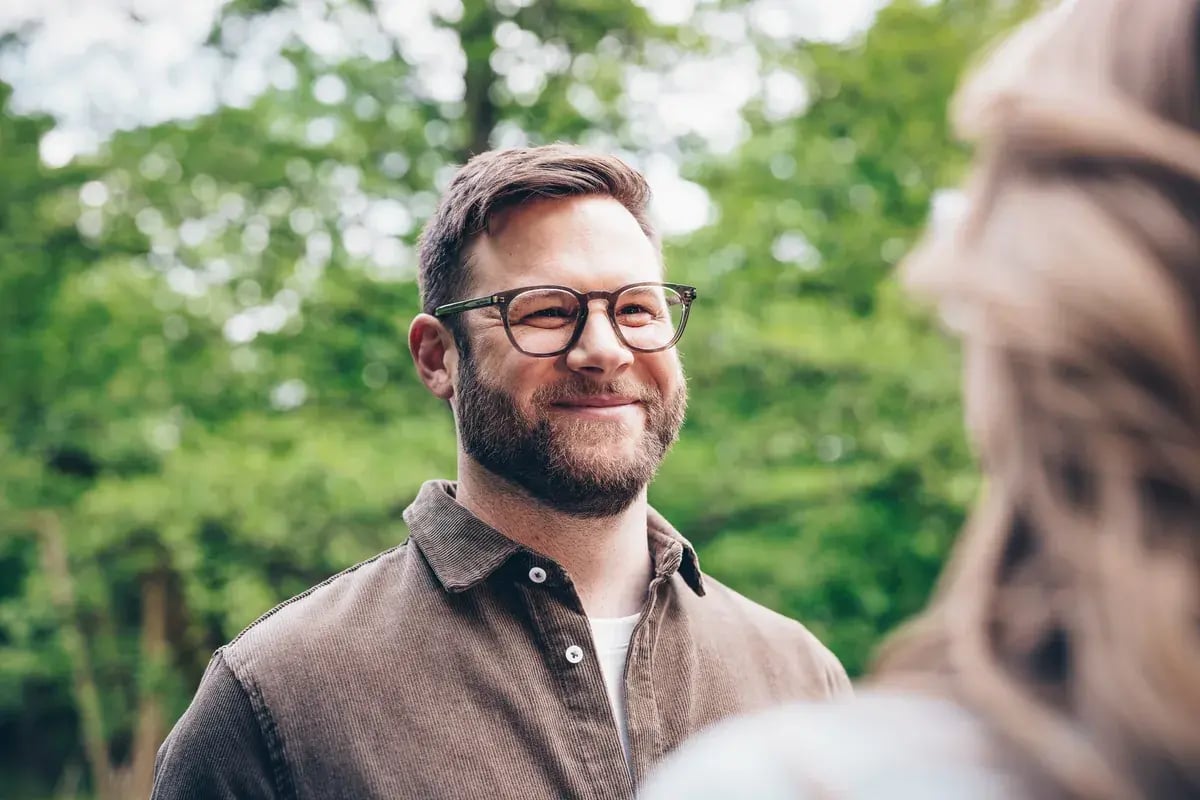 Mann mit Herrenbrille steht im Freien in der Natur