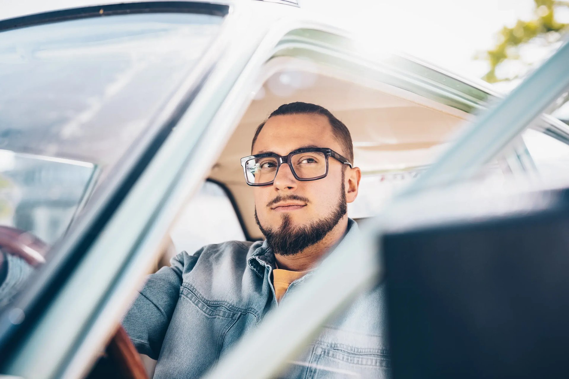 Mann mit Brille sitzt entspannt am Steuer eines Autos