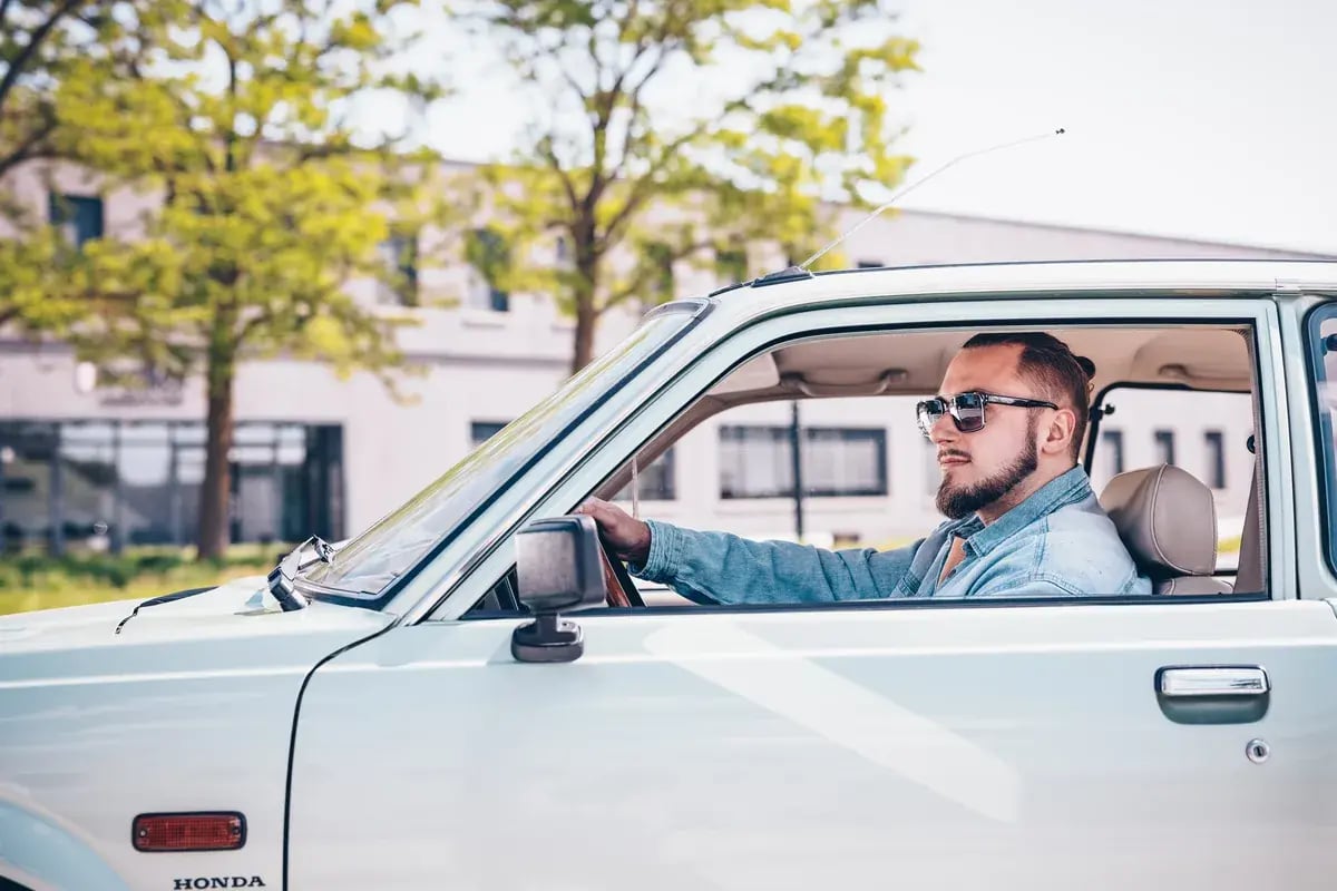 Mann mit Sonnenbrille am Steuer eines Honda beim Fahren