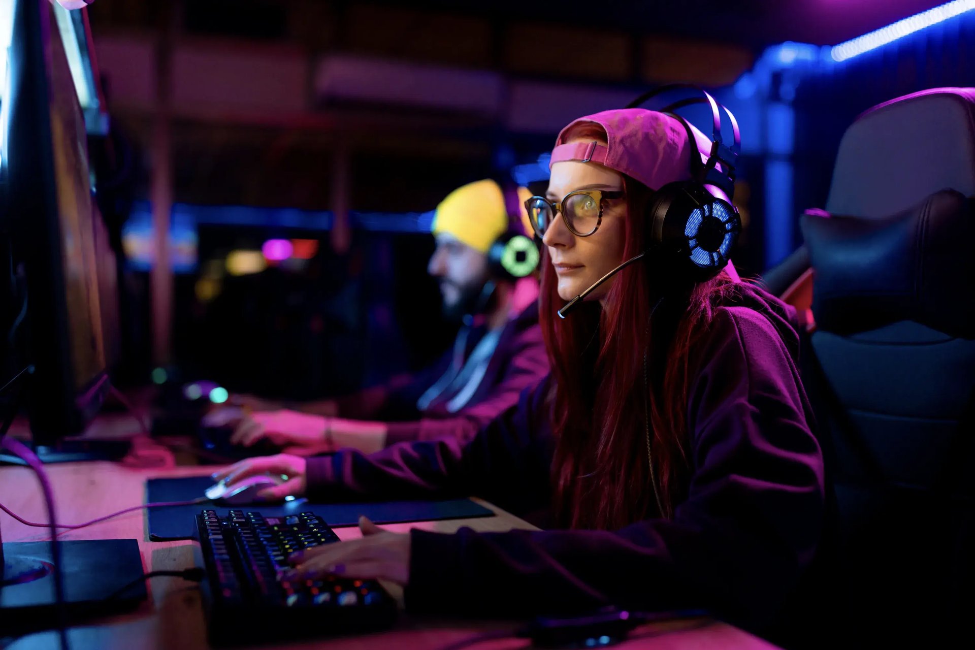 Gamer mit Gaming-Brille und Headset vor einem beleuchteten PC-Setup