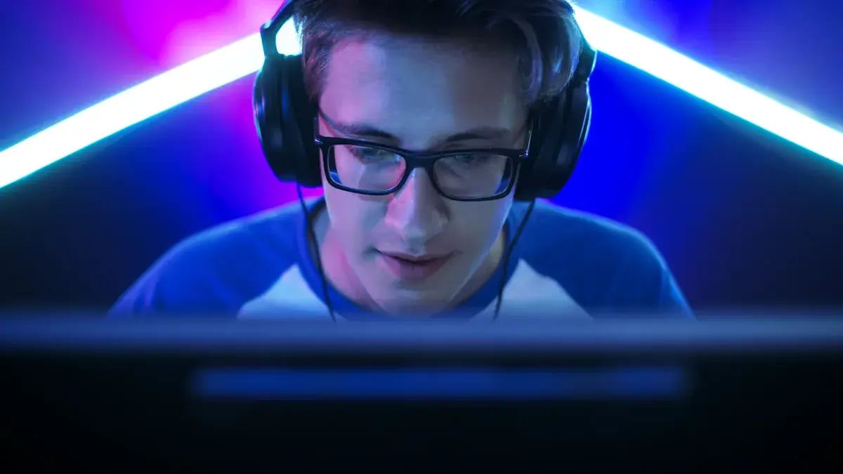 Mann mit Brille und Headset sitzt vor einem Gaming-Monitor