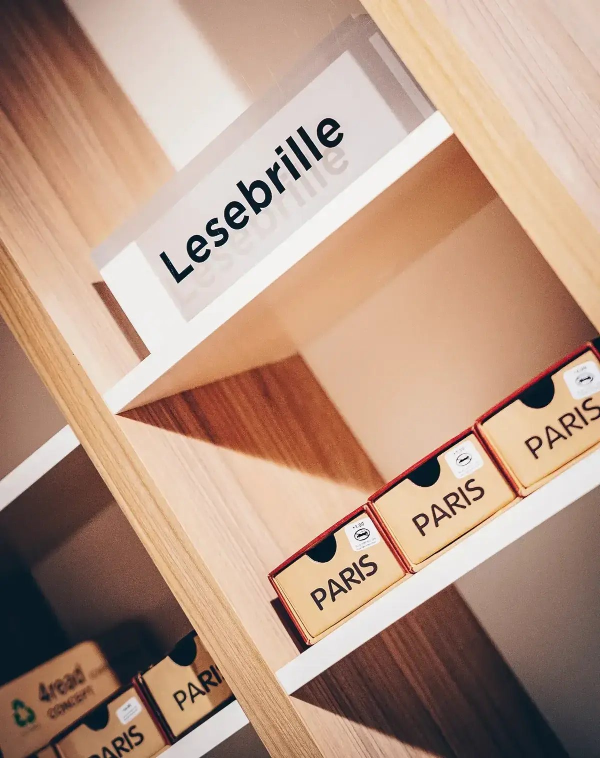 Lesebrillen stehen in Schachteln mit Paris-Beschriftung im Regal