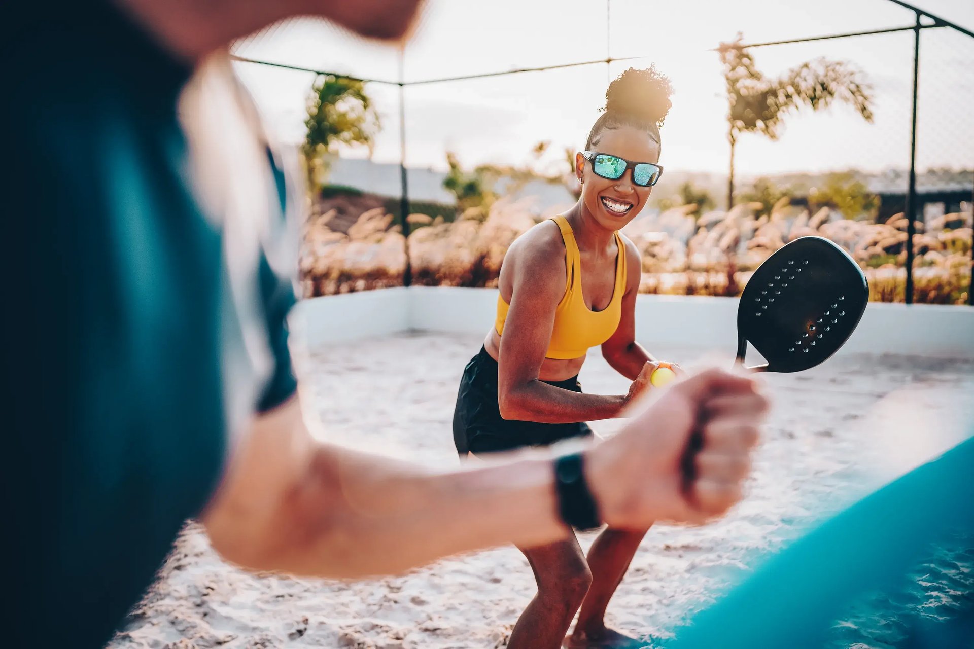 Frau mit Sportbrille hält einen Padelschläger im Freien