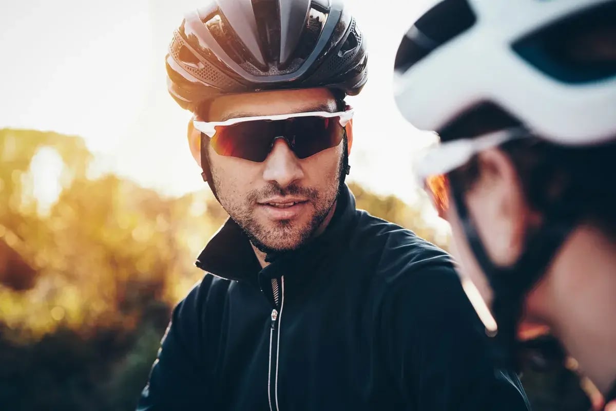 Radfahrer mit Sportbrille und Helm fährt auf einem Feldweg im Freien