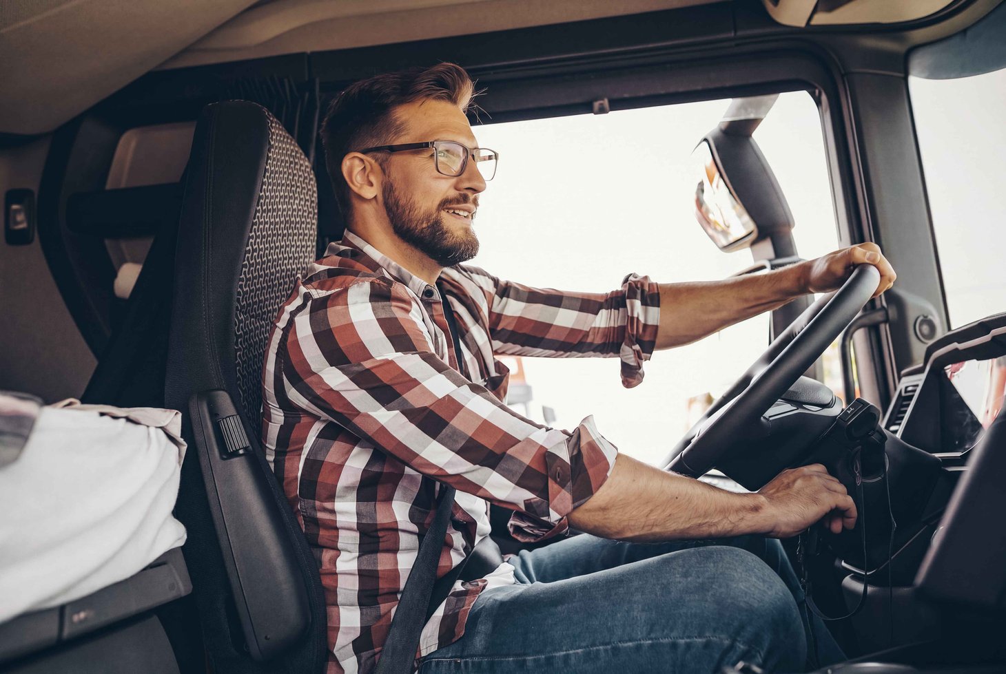 Ein junger LKW-Fahrer mit Brille fährt seinen Lastwagen