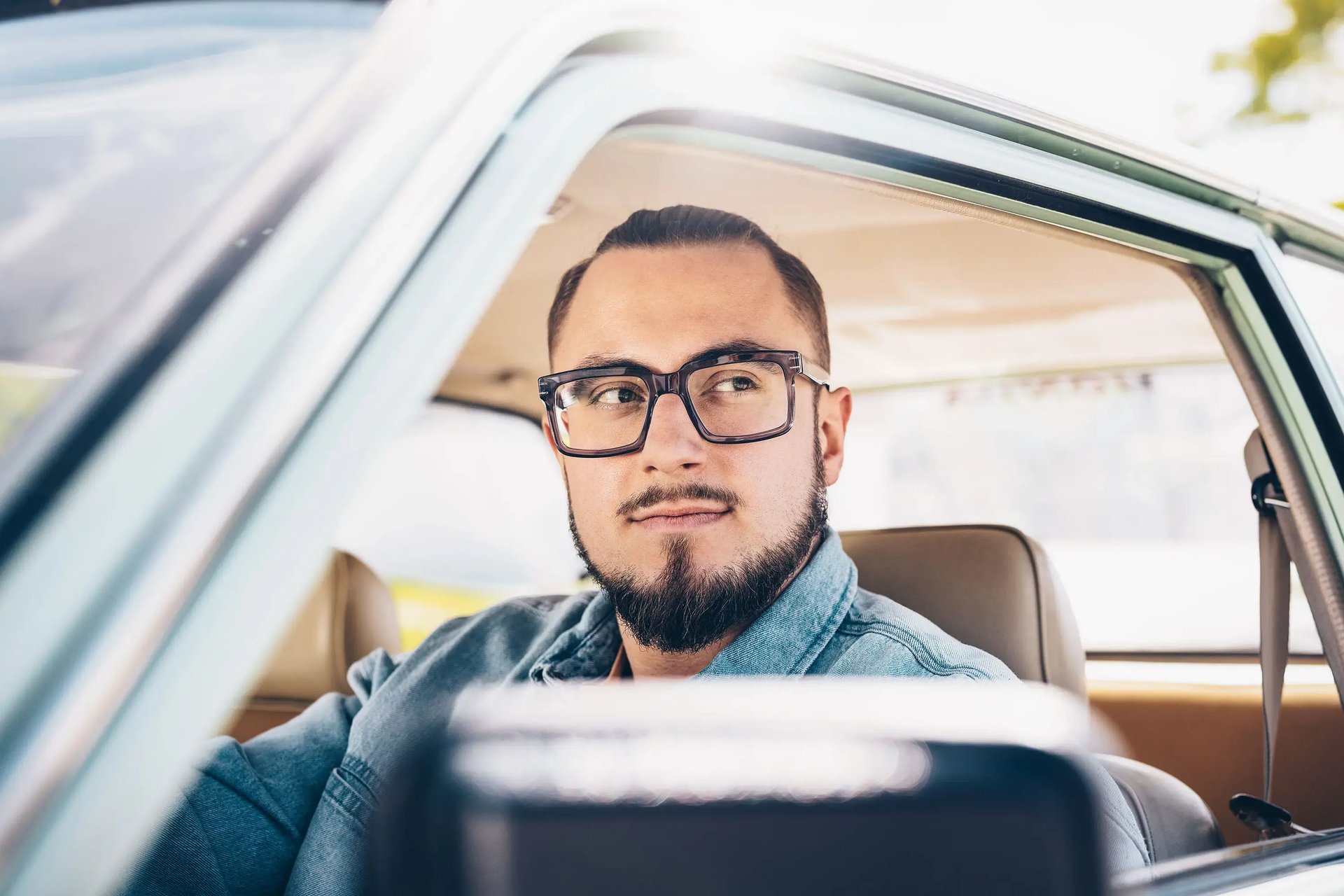 Mann mit Brille sitzt am Steuer eines Autos