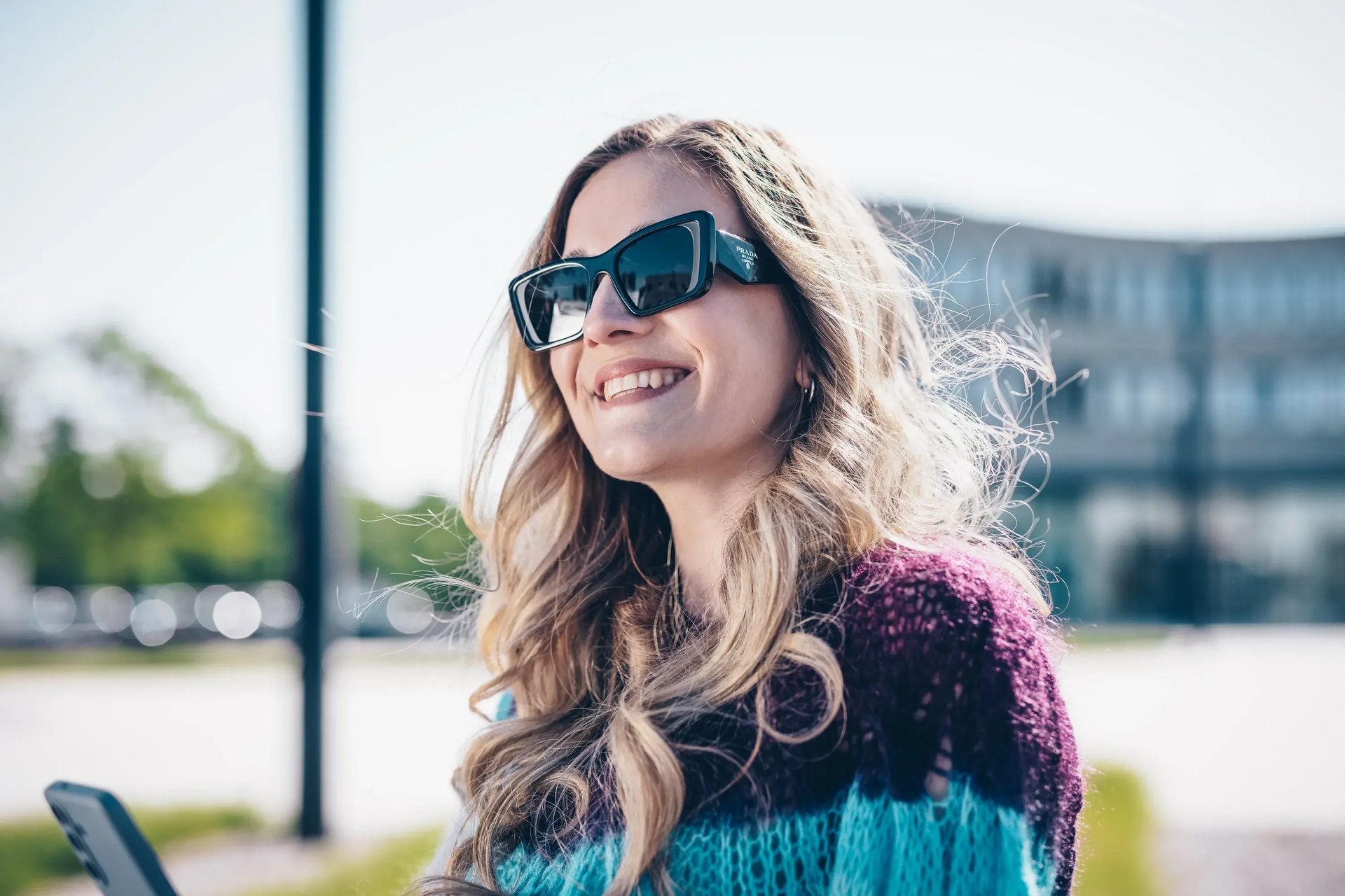 Frau mit schwarzer Cat-Eye-Sonnenbrille lächelt im Freien