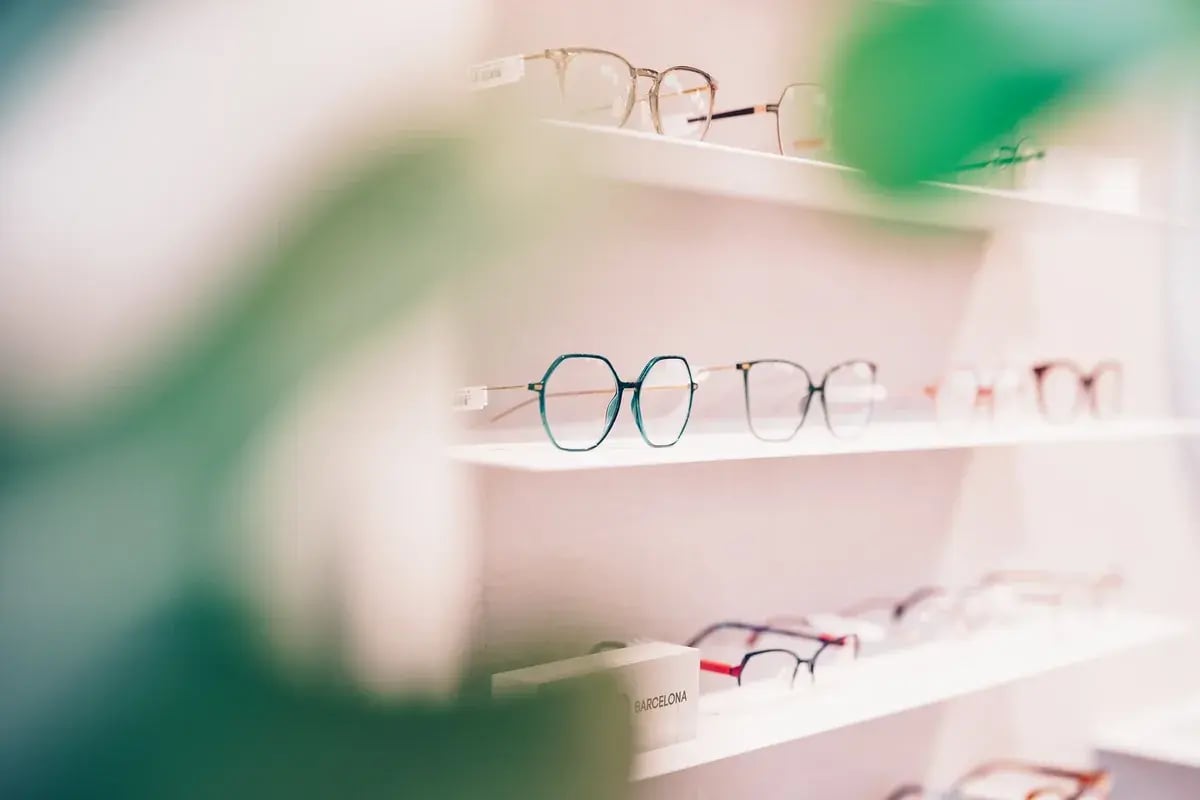 Mehrere Brillengestelle auf weißen Regalen in einem Optiker-Geschäft