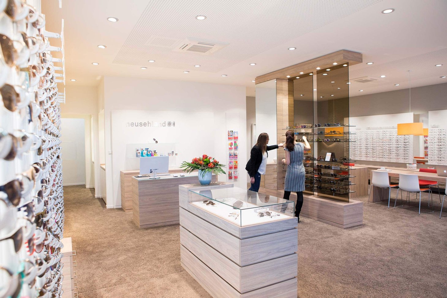 Zwei Frauen stehen im Innenraum eines Optikergeschäfts mit Brillenauslagen und Vitrinen
