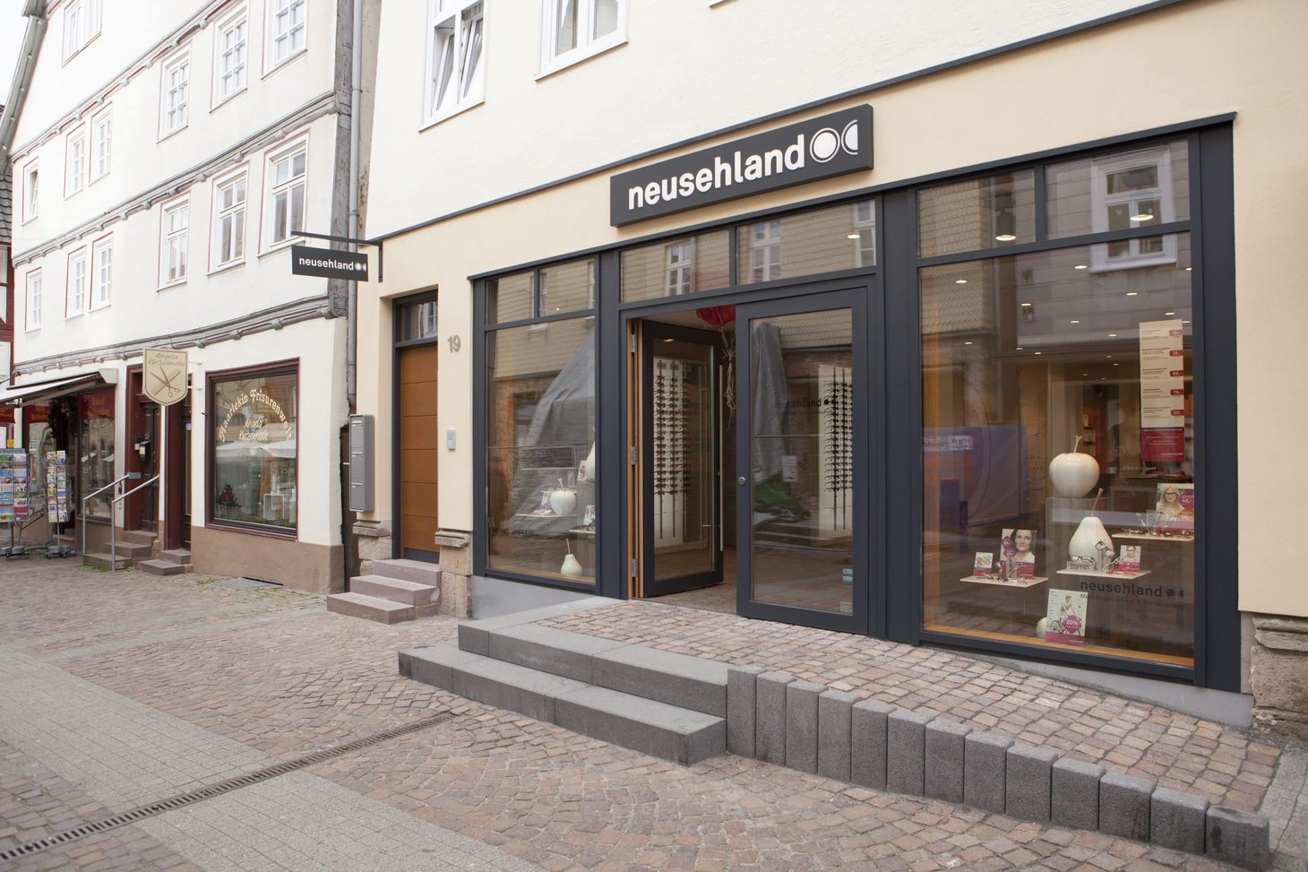 Ladenfront von neusehland in einer Fußgängerzone mit großen Schaufenstern und Pflastersteinboden