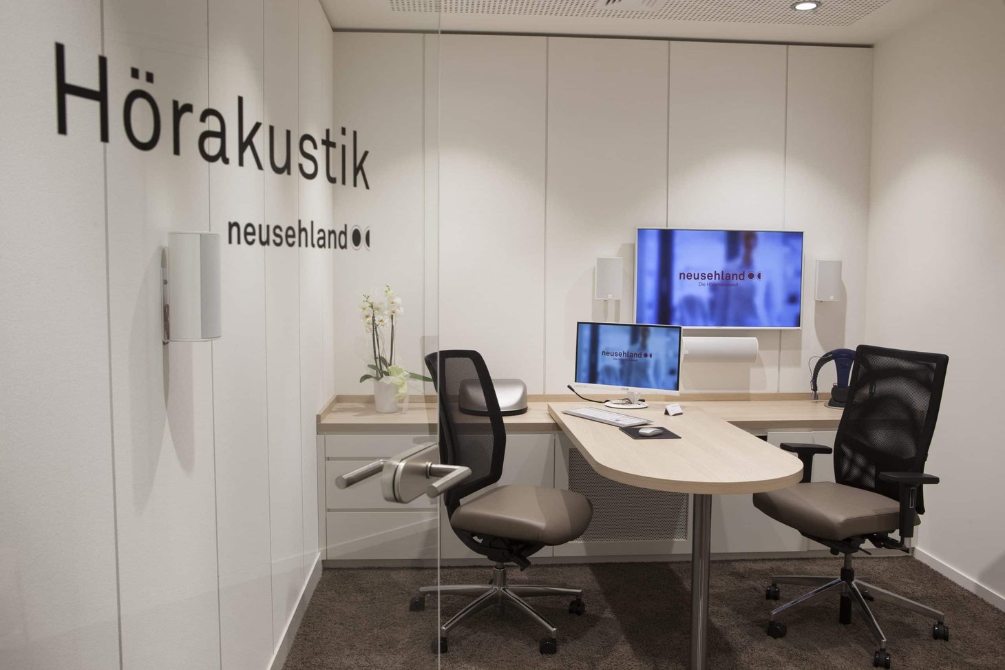 Beratungsraum mit Schriftzug "Hörakustik neusehland" an der Tür und zwei Bürostühlen