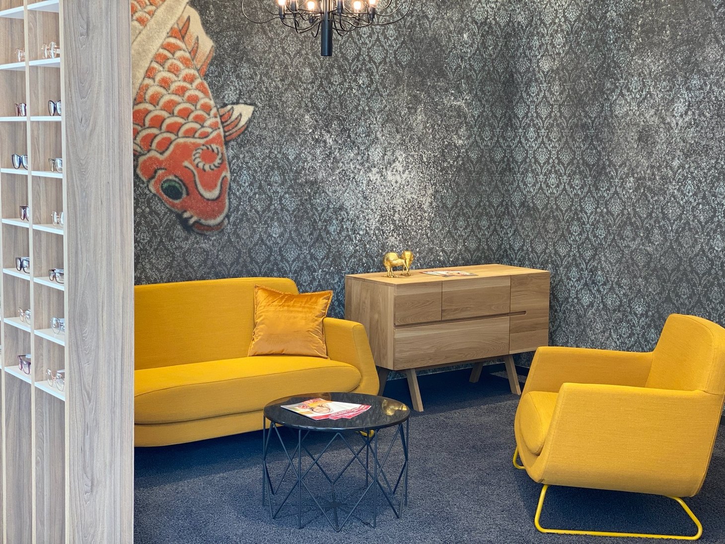 Wartebereich mit gelbem Sofa, Koi-Wandbild und grau gemusterter Tapete