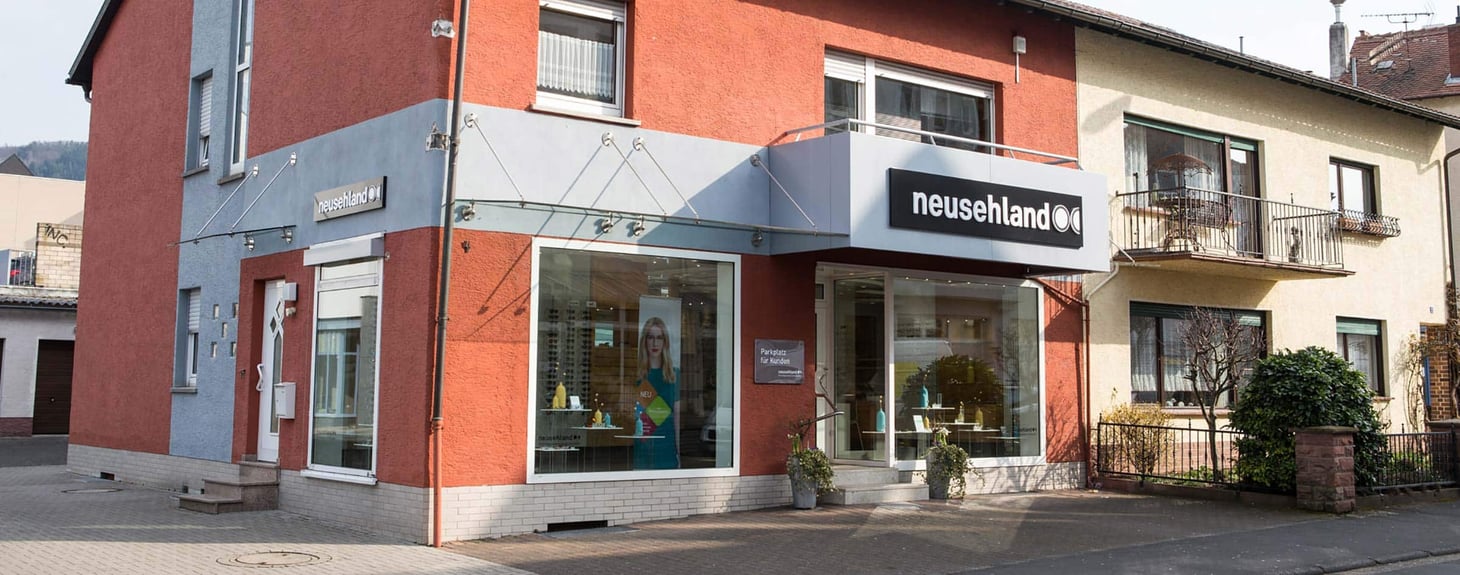 Außenansicht eines Eckgebäudes mit Schaufenster und Schriftzug "neusehland"