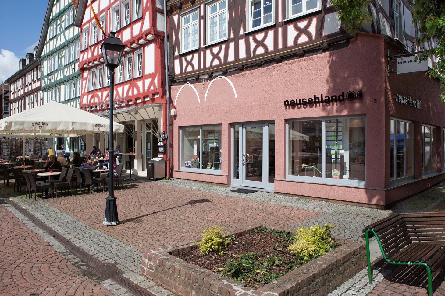 Filiale mit Schriftzug "neusehland" am Marktplatz zwischen Fachwerkhäusern