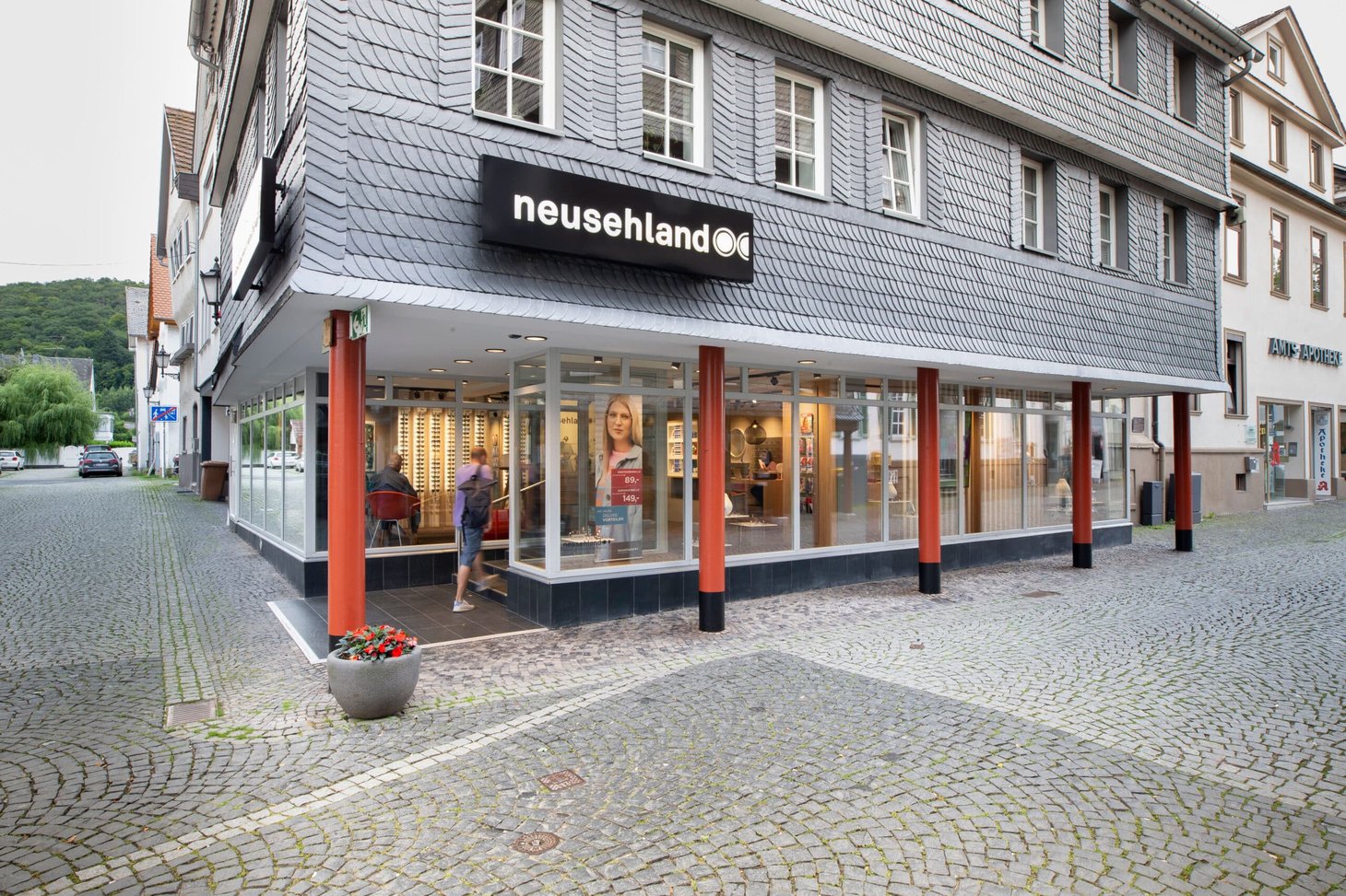 Optikgeschäft "neusehland" als Eckgebäude mit Glasfront und Kopfsteinpflaster