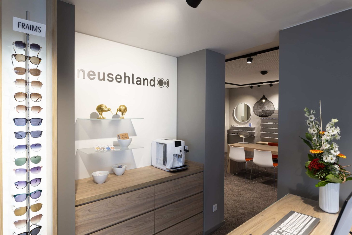 Empfangsbereich mit Schriftzug "neusehland" an der Wand und Produkte auf hellem Sideboard