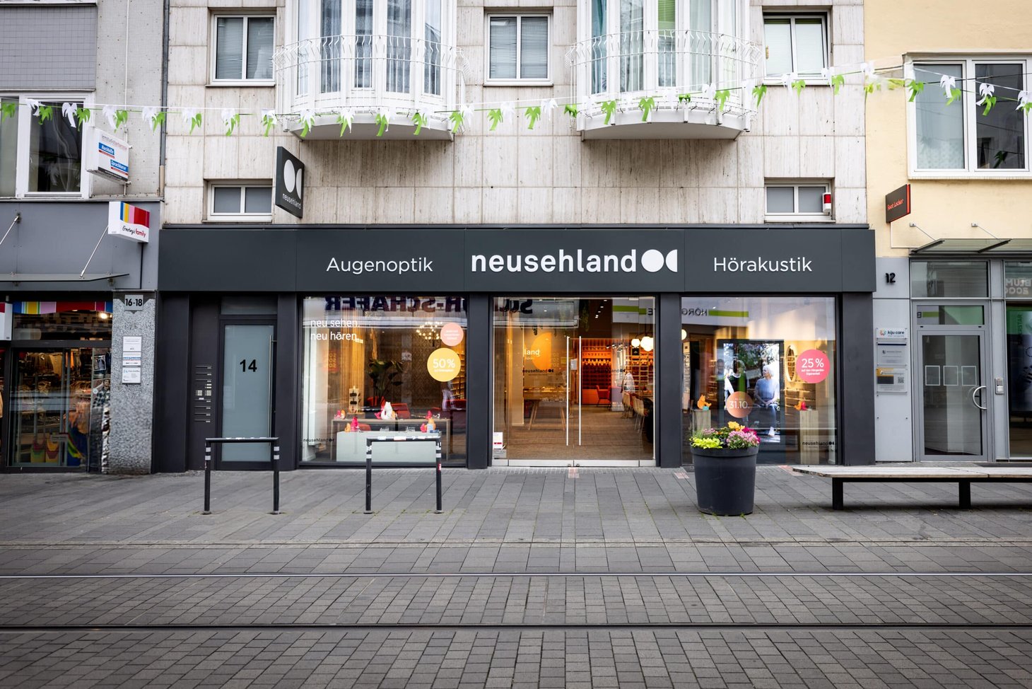 Ladenfront mit Schriftzug "Augenoptik neusehland Hörakustik" in einer Fußgängerzone