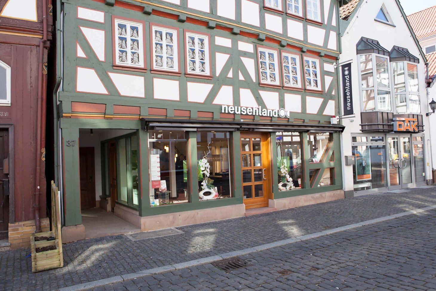 Filiale im Erdgeschoss eines Fachwerkhauses mit Schriftzug "neusehland" auf dem Schild