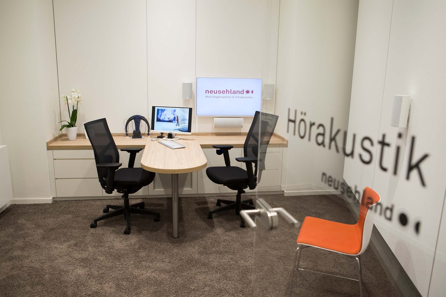 Beratungsraum mit Schriftzug "Hörakustik neusehland" an der Tür und zwei Bürostühlen