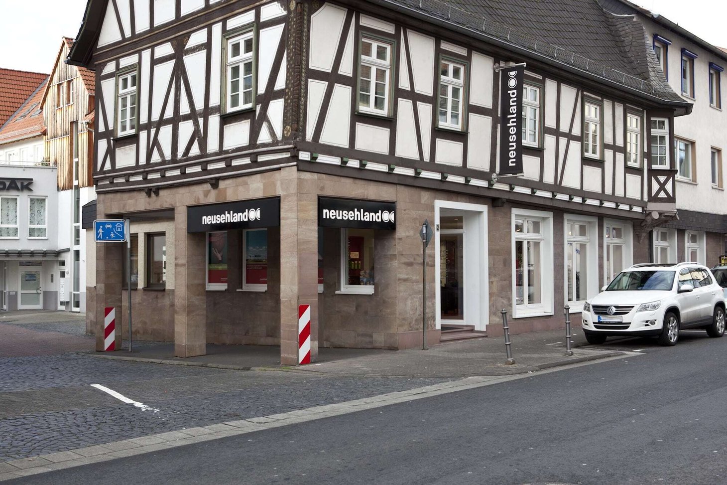 Eckgebäude mit Fachwerk und zwei Ladeneingängen mit Schriftzug "neusehland"