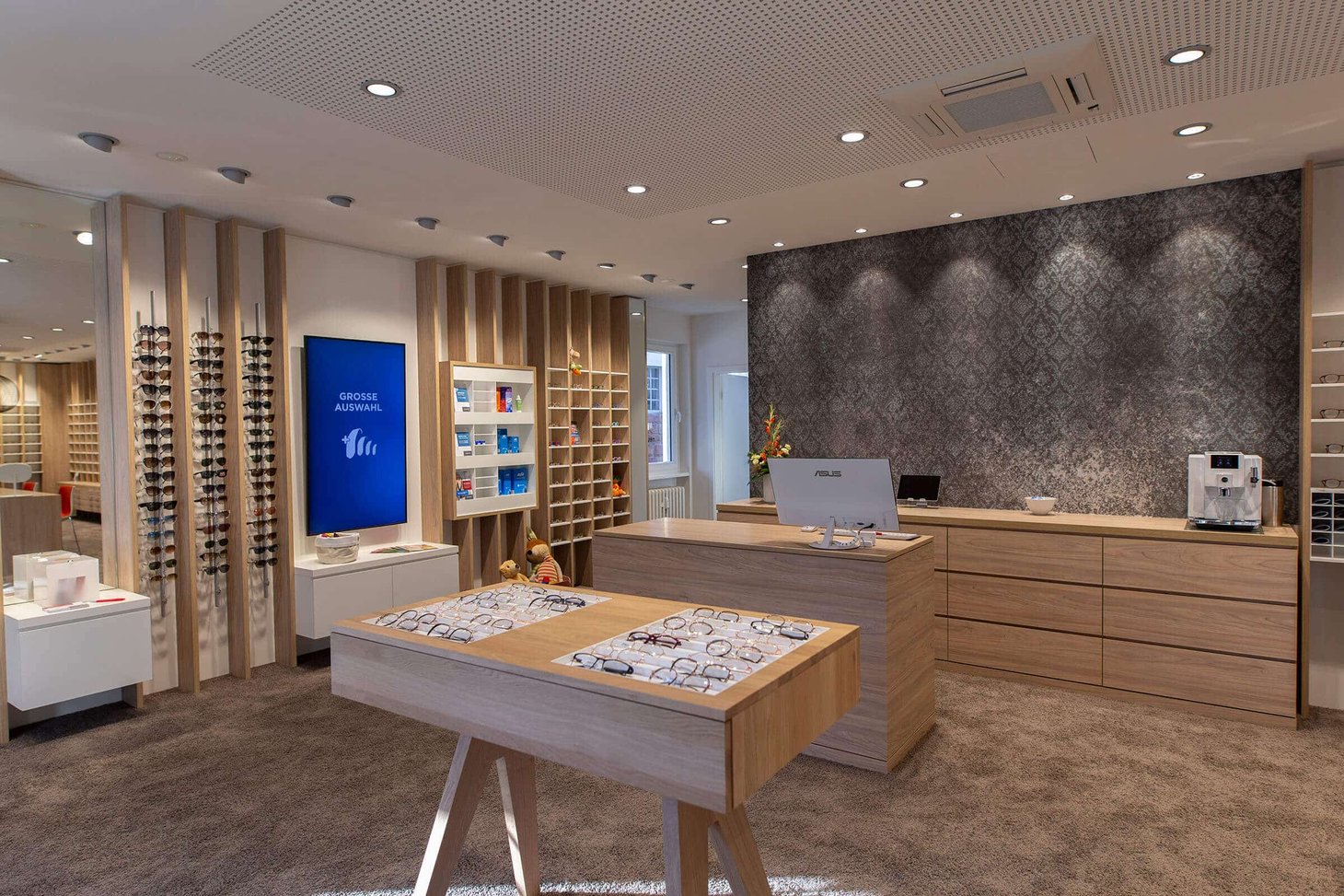 Empfangstresen eines Optikers mit Brillenvitrine und Display mit Aufschrift "Grosse Auswahl"