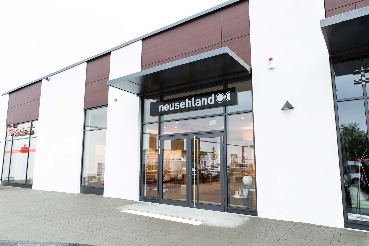 Eingang eines modernen Ladengebäudes mit schwarzem Schild und Schriftzug "neusehland"