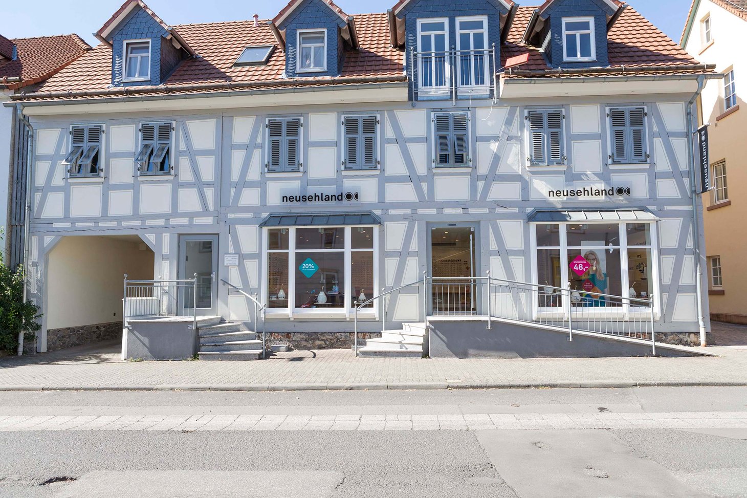 Fachwerk-Ladengebäude mit blau-weißer Fassade und zwei Schaufenstern mit Schriftzug "neusehland"