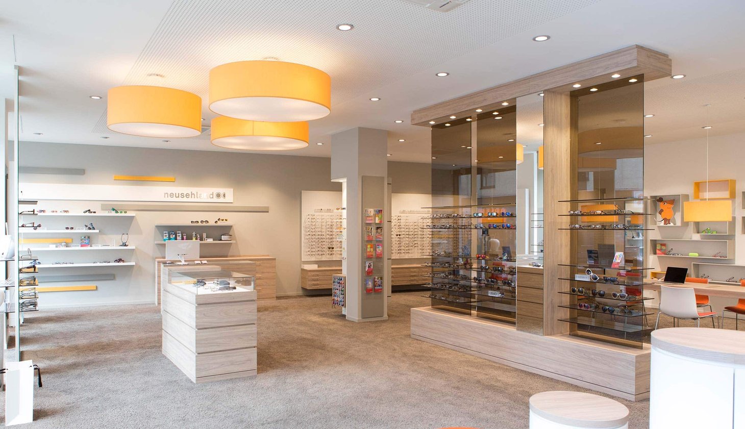 Optikergeschäft mit zwei runden orangen Hängelampen, Holzregal und Brillenauslagen