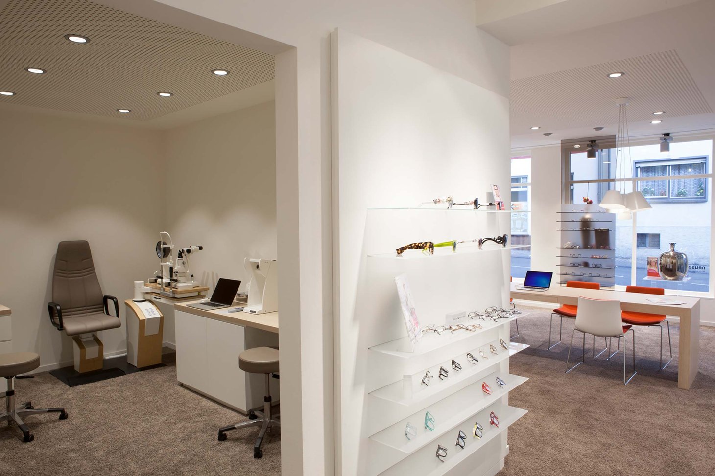 Optiker-Geschäft mit weißem Brillenregal und Blick in den Untersuchungsraum