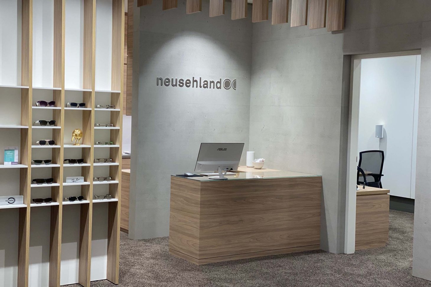 Empfangstheke aus Holz in einem Geschäft mit Schriftzug „neusehland" an der Wand
