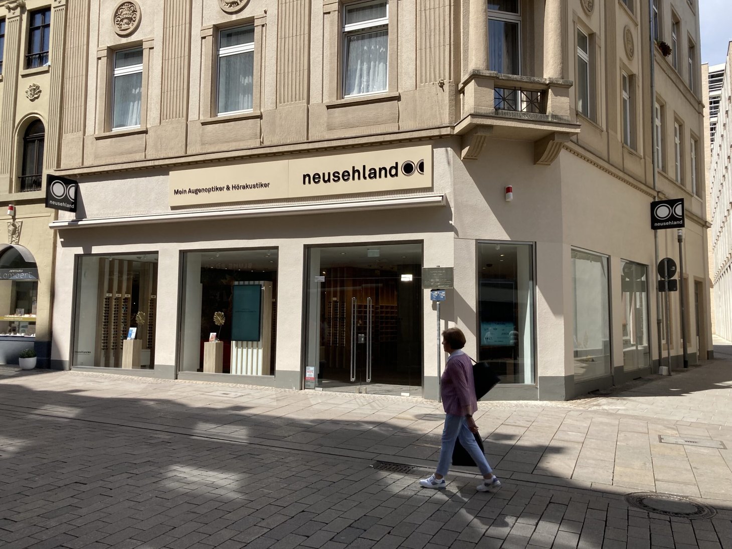 Außenansicht eines neusehland-Geschäfts in der Fußgängerzone, eine Person läuft vorbei