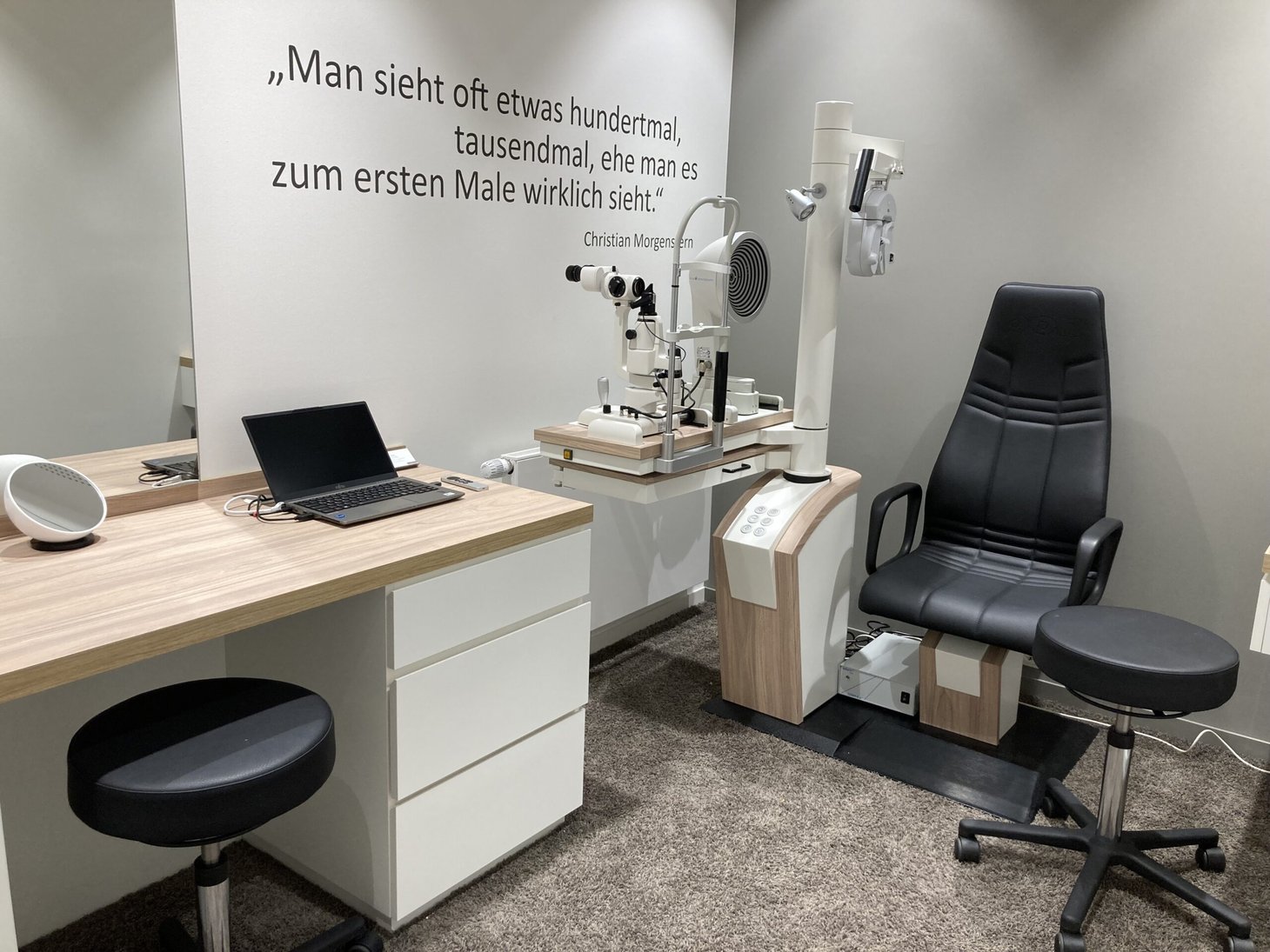 Untersuchungsraum mit Spaltlampe, Patientenstuhl, Schreibtisch und Laptop