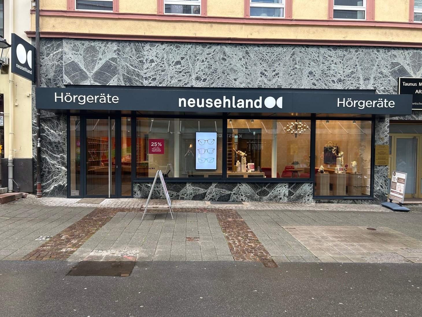 Außenansicht der neusehland-Filiale mit Schriftzug "Hörgeräte" an dunkler Fassade