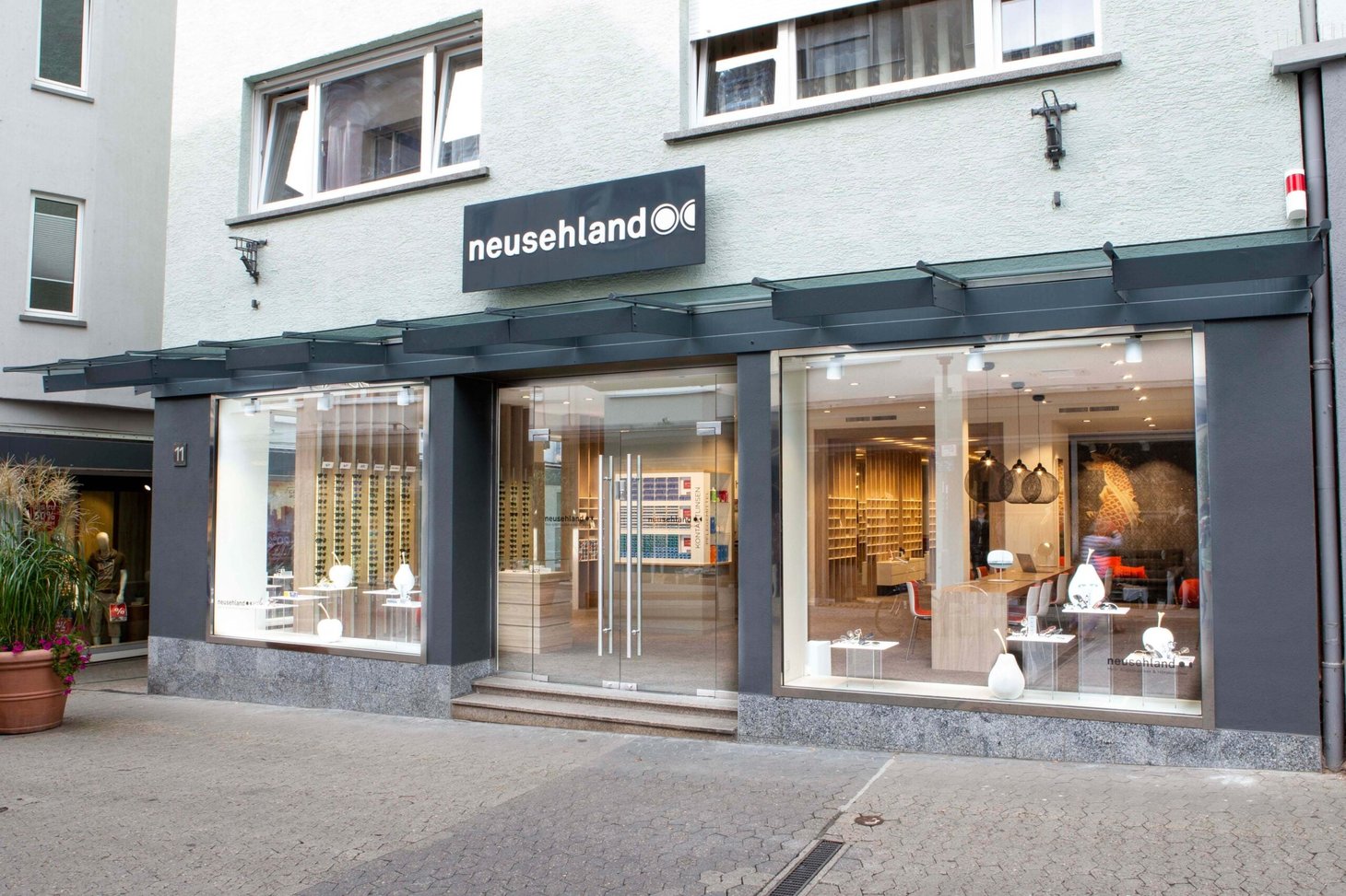 Außenansicht der neusehland-Filiale mit Schriftzug "neusehland" an grauer Fassade in der Fußgängerzone