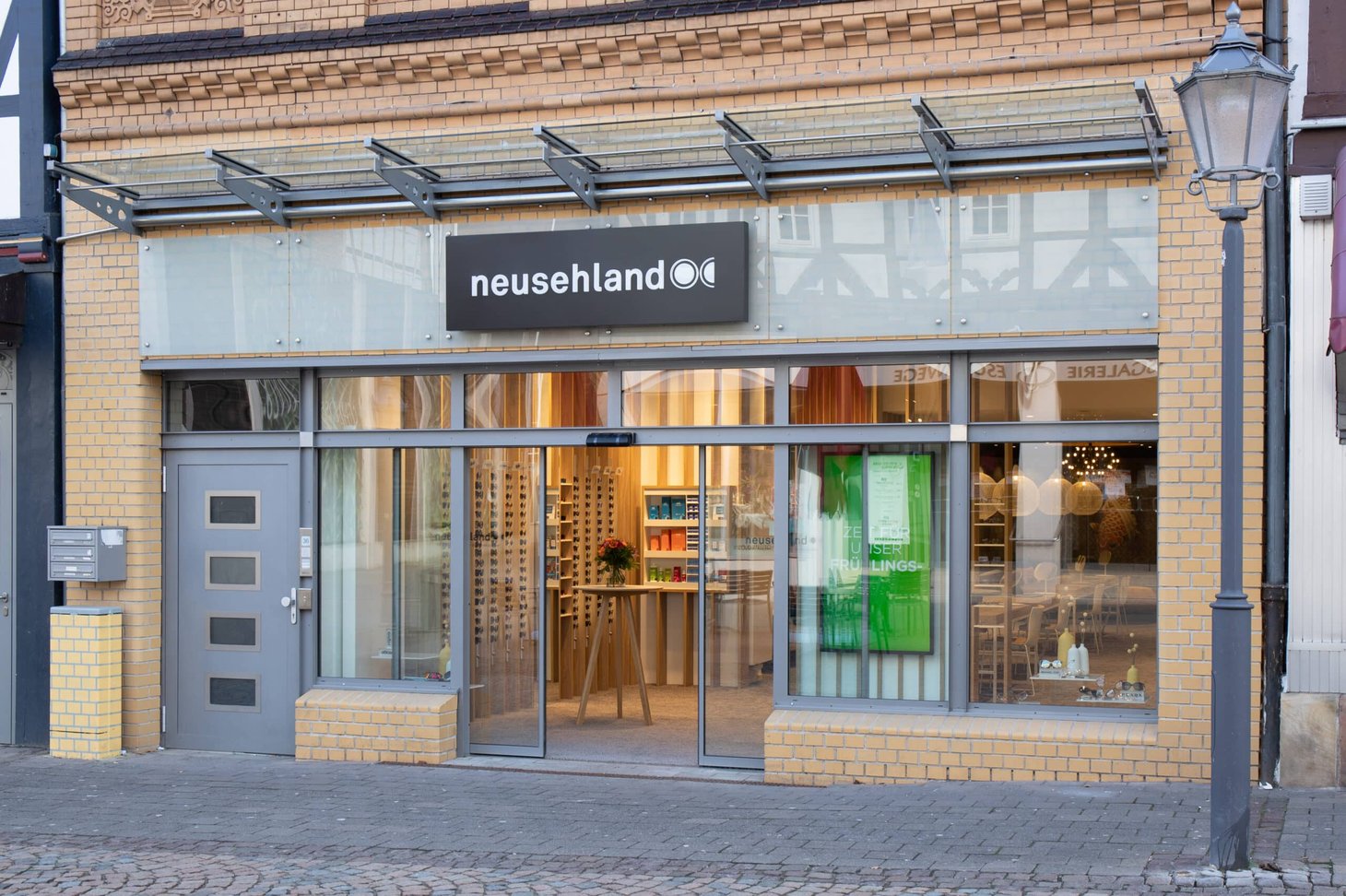 Ladenfront mit Schriftzug "neusehland" in gelbem Backsteingebäude mit Glasfront