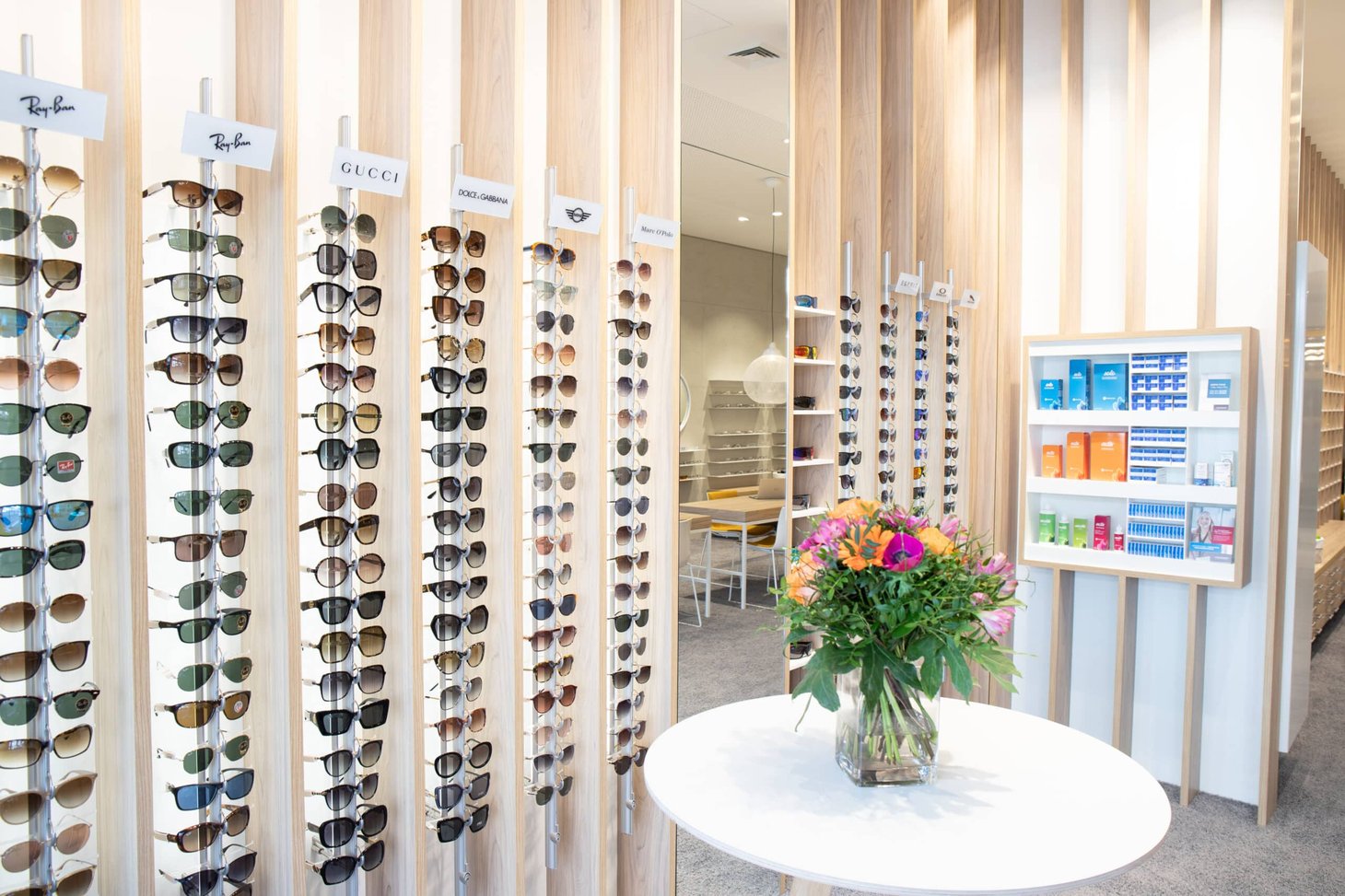 Sonnenbrillen-Display aus Holzstäben mit Markenschildern Ray-Ban und Gucci