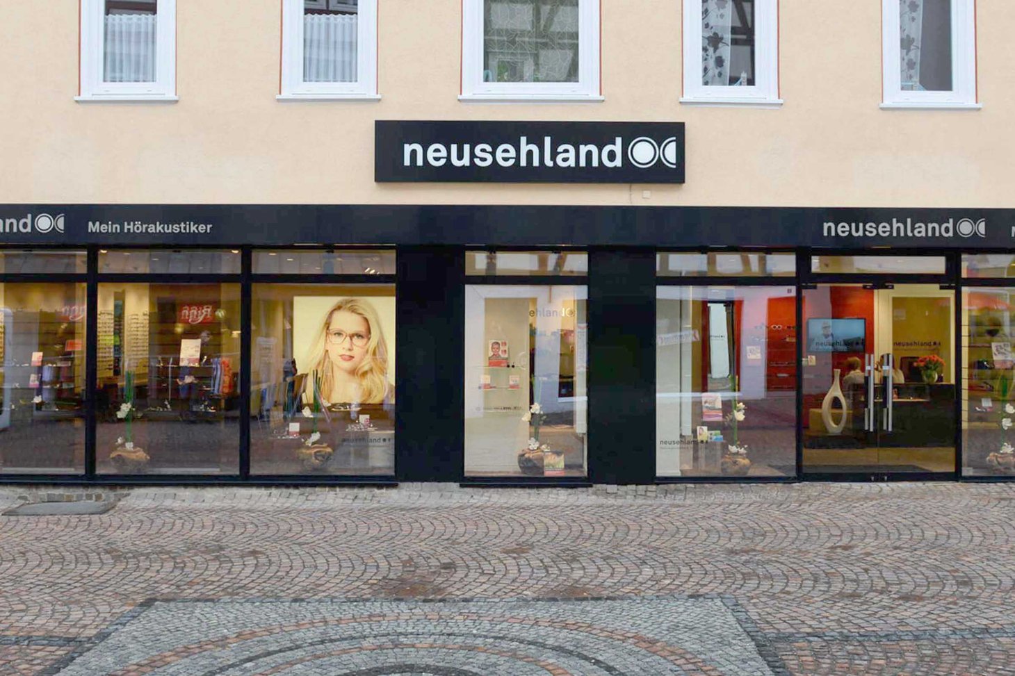 Ladenfront mit Schriftzug "neusehland" auf schwarzer Fassade, zwei Schaufenster