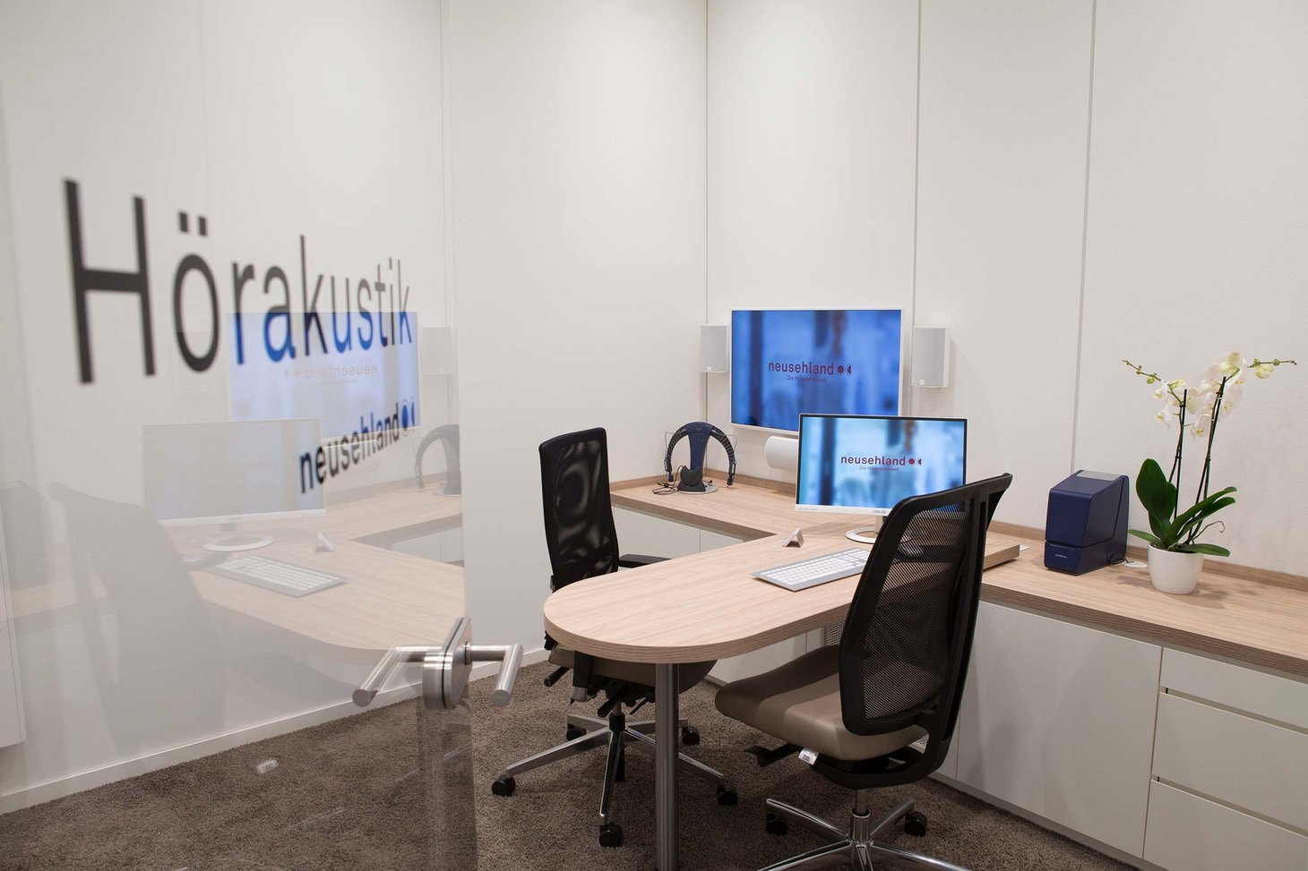Beratungsraum mit Schriftzug "Hörakustik neusehland" an der Tür und zwei Bürostühlen
